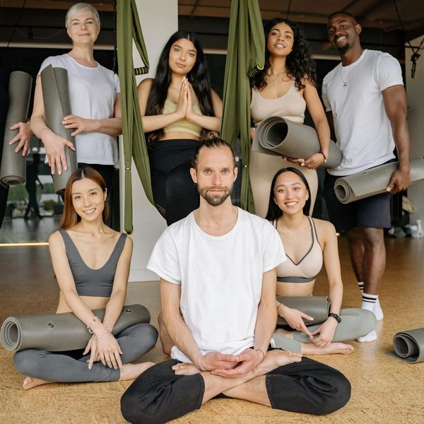 A diverse group of people sitting peacefully in a bright yoga studio.