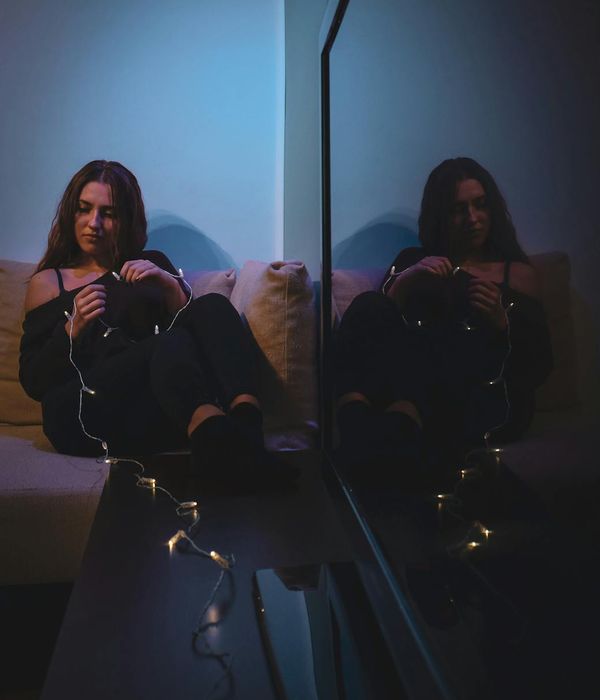 Woman in a calm yoga pose in a dark room with soft lighting.